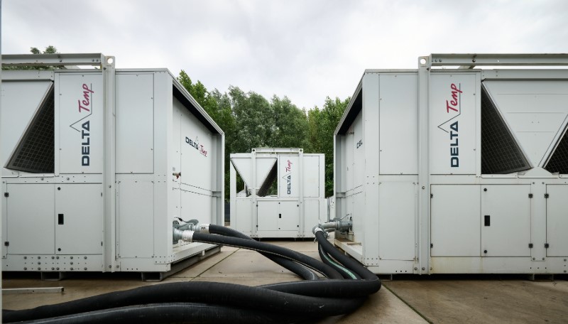 Drie grote witte Delta-Temp koelunits met donkere slangen op de voorgrond, opgesteld op een betonnen ondergrond onder een bewolkte hemel.